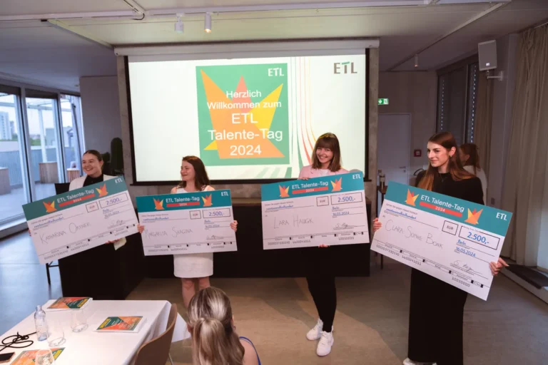 Preisverleihung für die Auszubildenden bei ETL. 4 Azubis halten einen großen Weiterbildungsgutschein in der Hand.